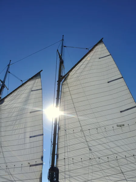 Zon tussen grootzeil en eenmansboot van schoener zeilboot — Stockfoto