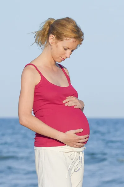 Беременная женщина на пляже — стоковое фото