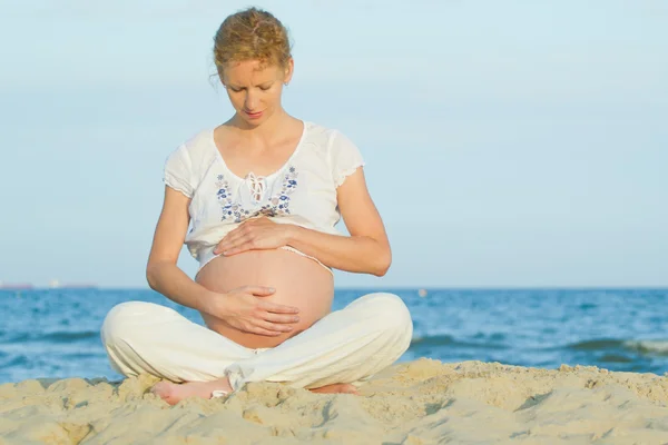 Gravid kvinna på strand Stockfoto