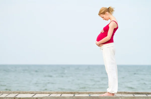 Gravid kvinna på strand Stockfoto