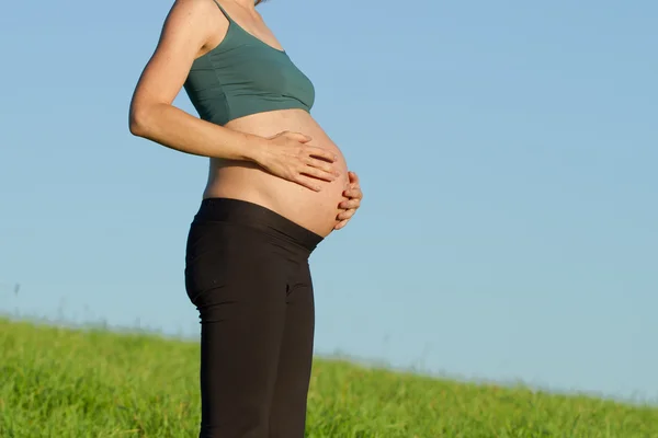 Hamile kadın üzerinde çayır — Stok fotoğraf