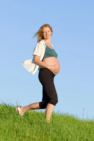 Pregnant woman on meadow Stock Picture