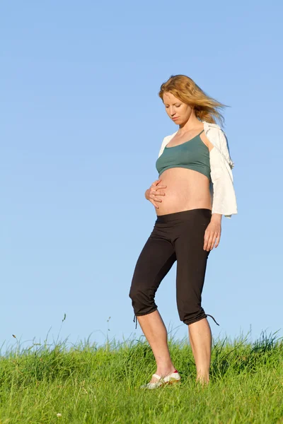 Pregnant woman on meadow Stock Picture