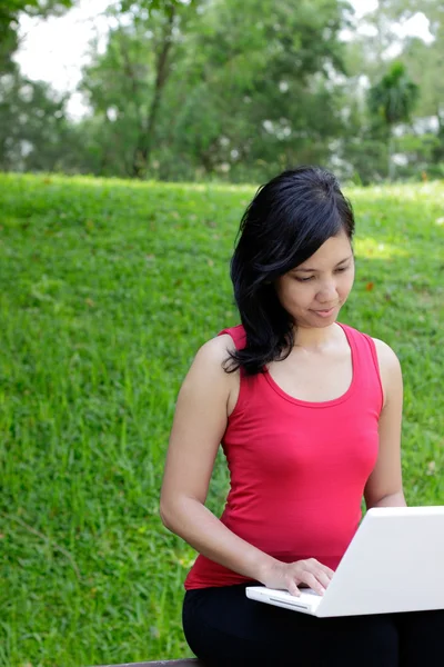 Женщина в парке с ноутбуком — стоковое фото