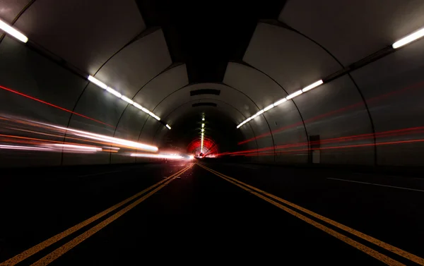 Pojazdy przechodzi szybko w tunelu, pozostawiając smugi światła — Zdjęcie stockowe