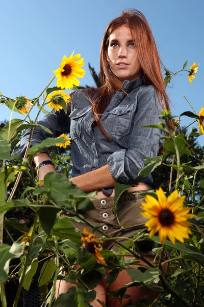 Червоні волосся жінка на відкритому повітрі в поле соняшникова — стокове фото