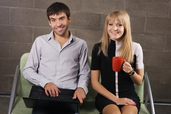 Giovane uomo e donna seduti con un computer portatile — Foto Stock