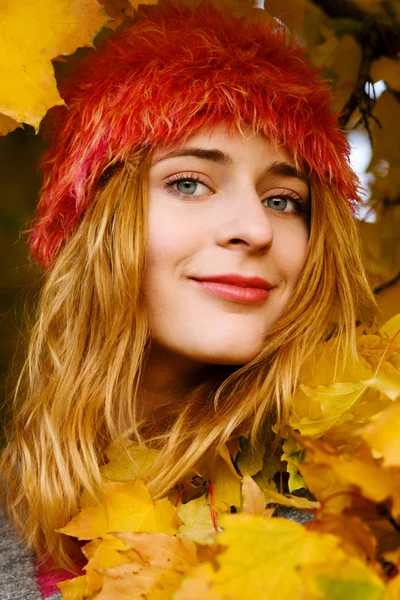 Beautiful young woman among yellow leaves — Stock Photo, Image