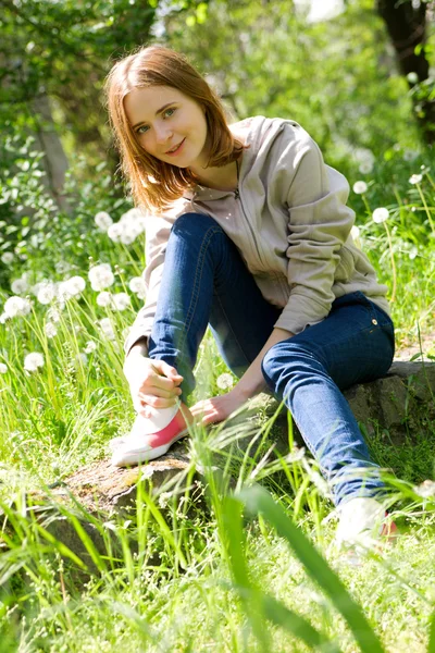 Schöne junge Frau sitzt in Löwenzahn — Stockfoto
