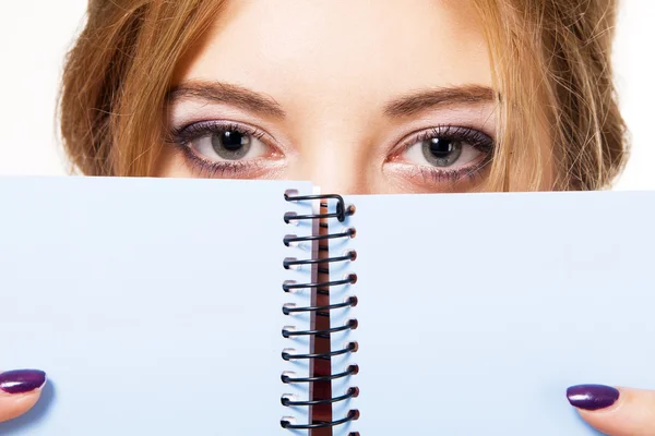 Härlig tjej som gömmer sig bakom notebook — Stockfoto