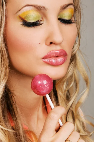 Mujer joven con maquillaje vibrante sosteniendo una piruleta — Foto de Stock