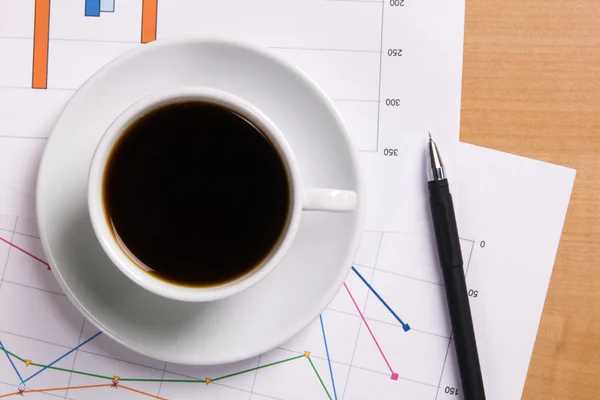 Cup of strong coffee over business diagrams — Stock Photo, Image