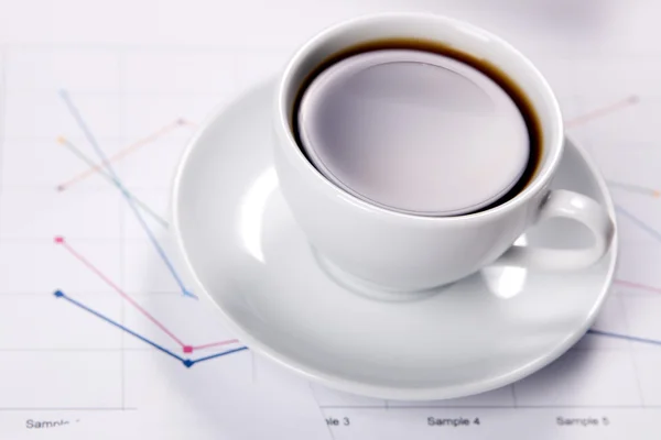 Kopje sterke koffie over zakelijke diagrammen — Stockfoto
