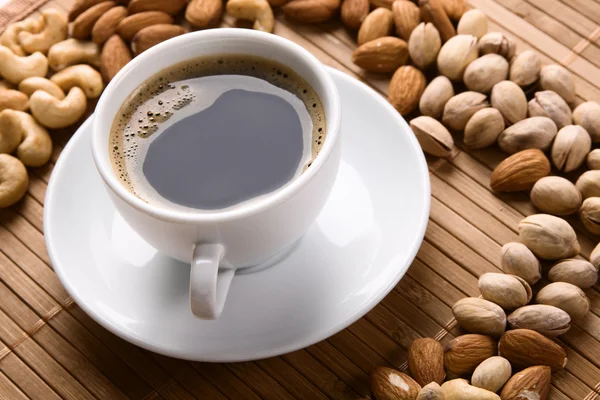 White cup of coffee with lot of nuts — Stock Photo, Image