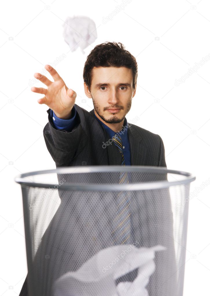 Young businessman throwing paper at trash can