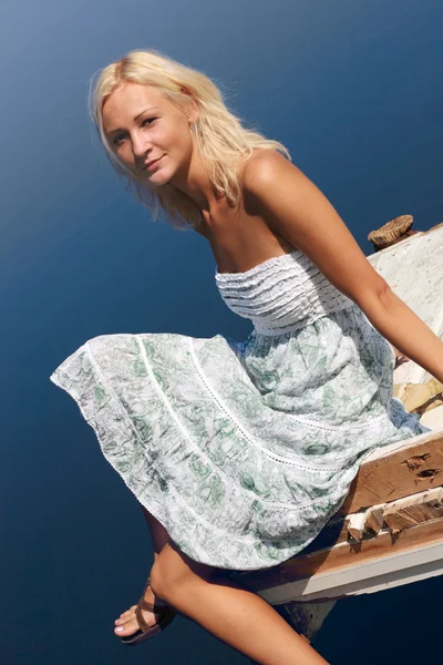 Meisje, zittend op een pier bij de rivier bank — Stockfoto