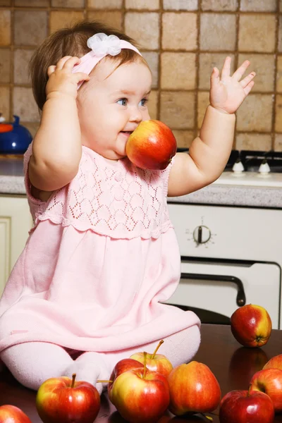 Liten flicka spelar med röda äpplen — Stockfoto