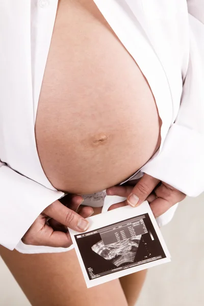 Mujer embarazada joven sosteniendo una impresión de prueba ultrasónica — Foto de Stock