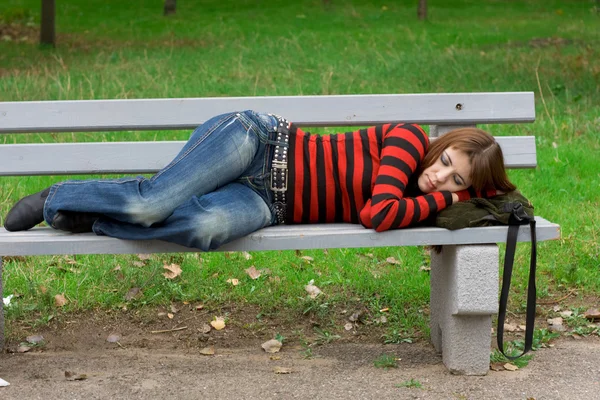 Menina dormindo em um banco de parque — Fotografia de Stock