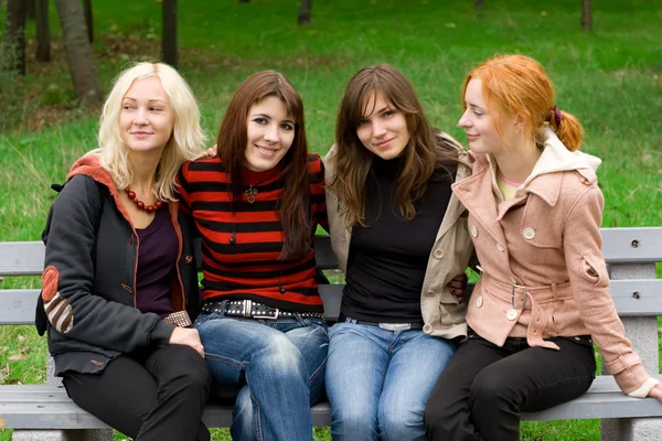 Cuatro chicas sentadas en un banco del parque — Foto de Stock