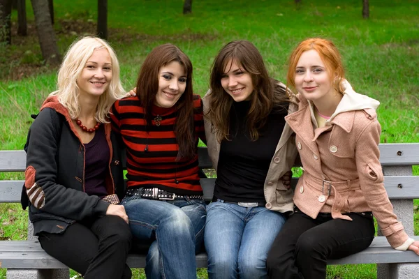 Čtyři dívky sedící na lavičce v parku — Stock fotografie