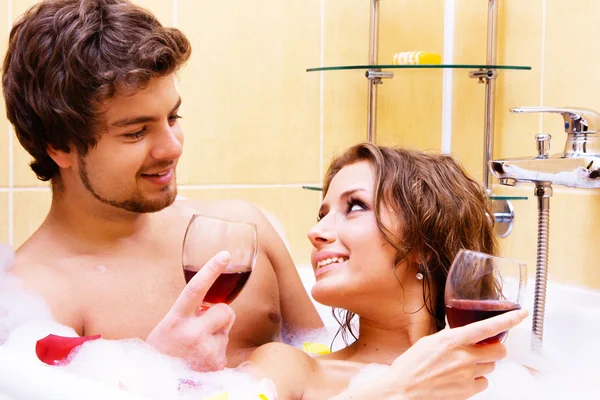 Молодая пара пьет вино в ванной — стоковое фото