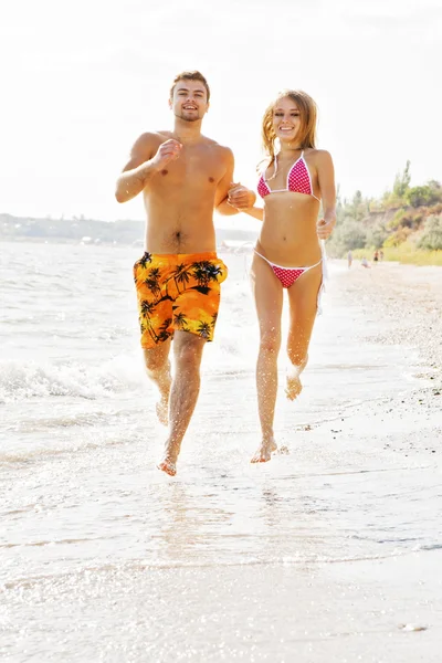 Молодая пара бежит вдоль пляжа — стоковое фото