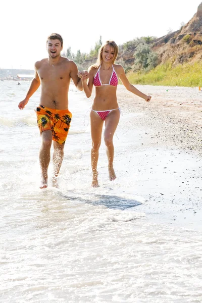 Young couple running along the beach — Stock Photo, Image