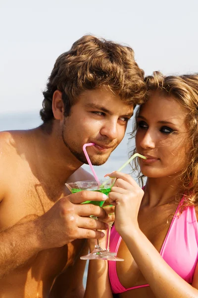 Mladý pár s koktejly na moře — Stock fotografie