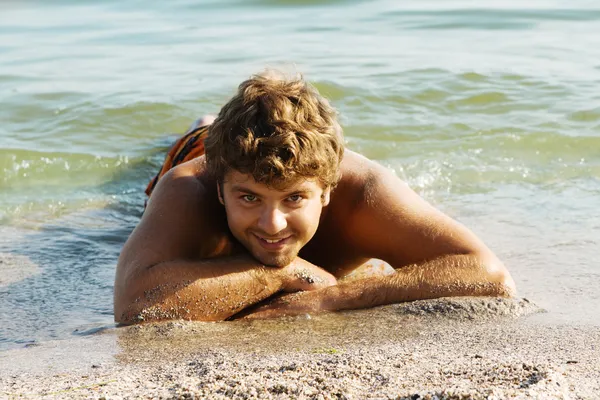 Genç adam rahatlatıcı bir deniz kıyısında — Stok fotoğraf