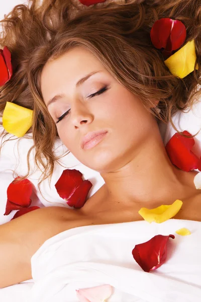 美しい若い女性はバラの花びらで横になっています。 — ストック写真