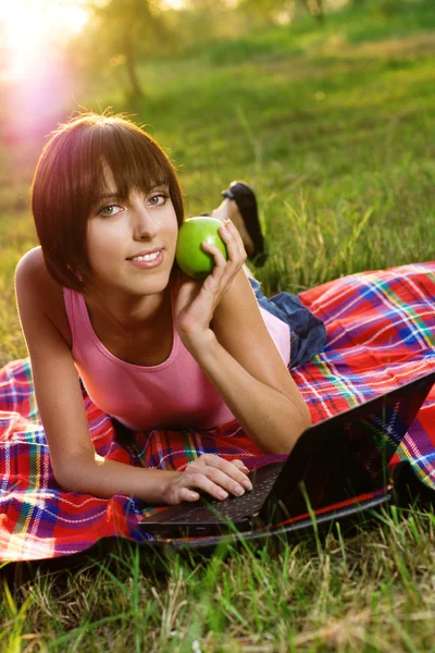 Härlig tjej med laptop i parken — Stockfoto