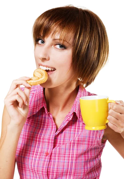 Menina bonito com uma xícara de chá mordendo um pretzel — Fotografia de Stock
