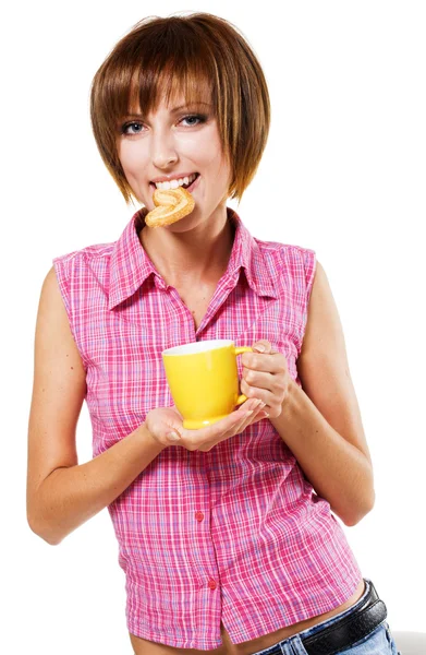 Милая девушка с чашкой чая, кусающая крендель — стоковое фото