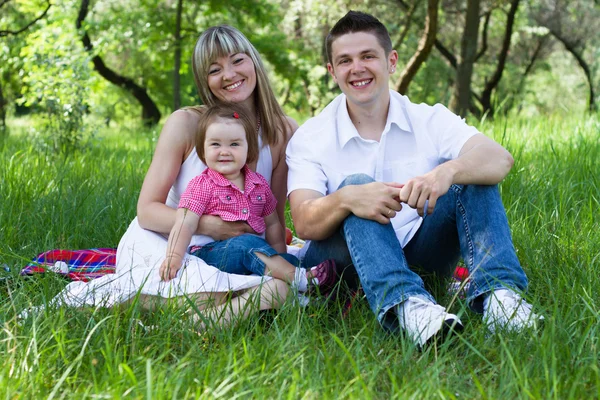 Ung familj av tre på en picknick — Stockfoto