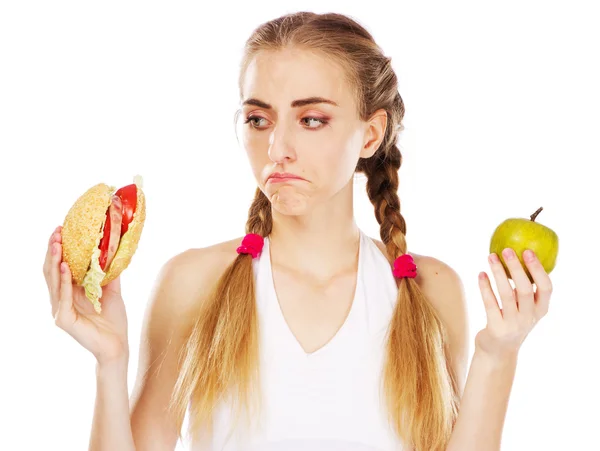 Młoda kobieta wybierając między hamburgera i jabłko — Zdjęcie stockowe