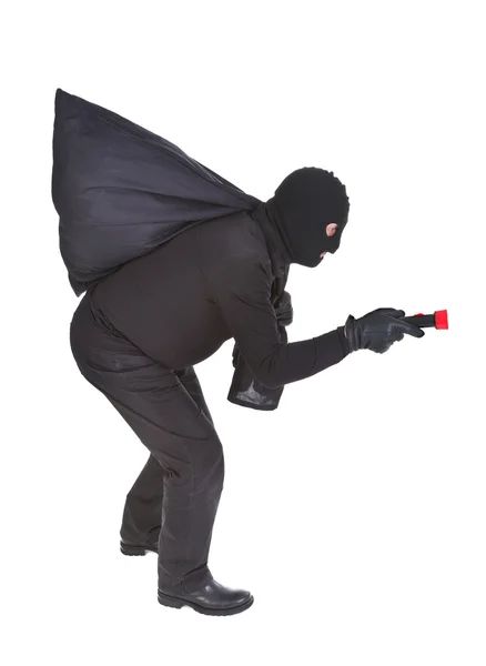 Robber with flashlight and sack — Stock Photo, Image