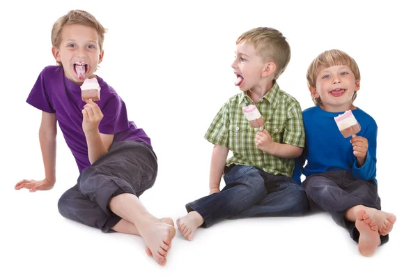 Troje dzieci śmieszne jedzenie lody na patyku — Zdjęcie stockowe