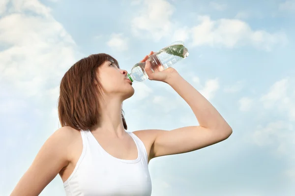 Mujer atlética joven bebiendo agua mineral — Foto de Stock