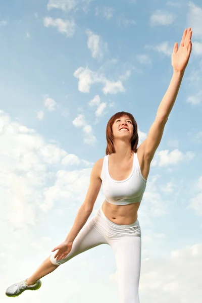Donna atletica in equilibrio davanti al cielo blu — Foto Stock