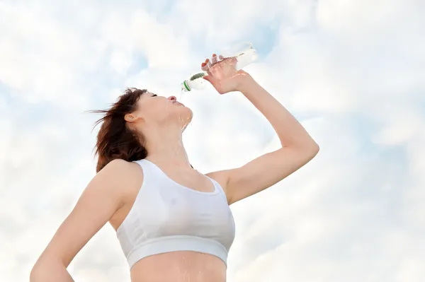 Mujer atlética agotada bebiendo agua mineral — Foto de Stock