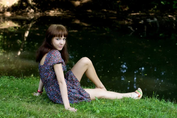 Красивая девушка сидит на берегу реки — стоковое фото