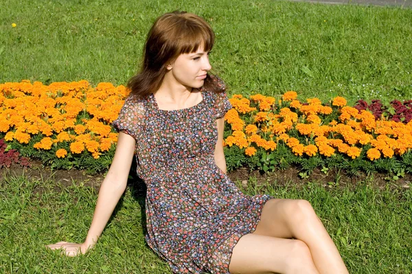 美丽的女孩坐在草地上用鲜花 — 图库照片