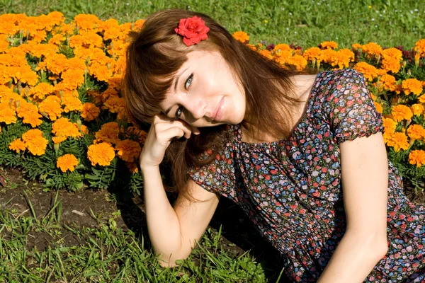 Hermosa chica sentada en el prado con flores —  Fotos de Stock