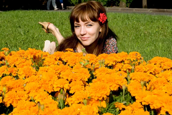 Piękna dziewczyna leżąc na łące z kwiatami — Zdjęcie stockowe