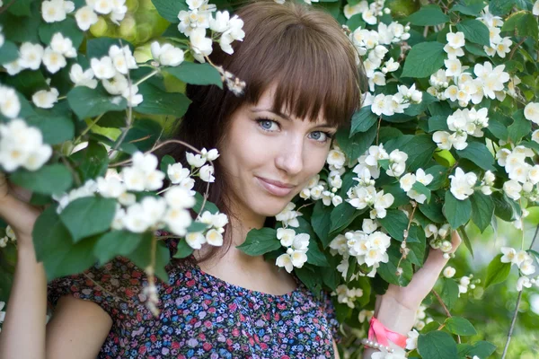 Retrato de cerca de una hermosa niña de pie entre flores — Foto de Stock