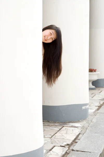 Menina bonita escondendo entre colunas — Fotografia de Stock