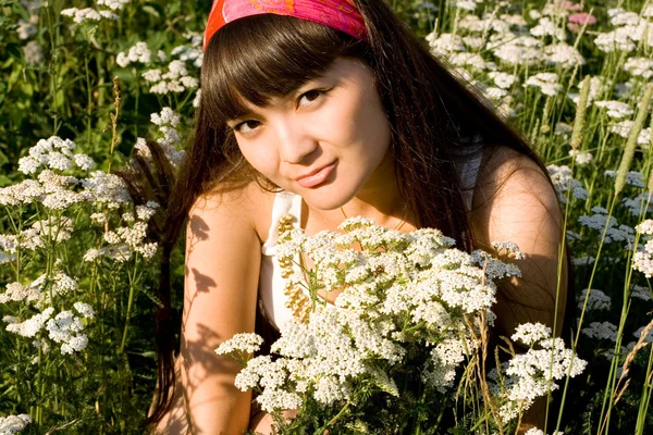 花の牧草地の上に座って美しい少女 ロイヤリティフリーのストック画像