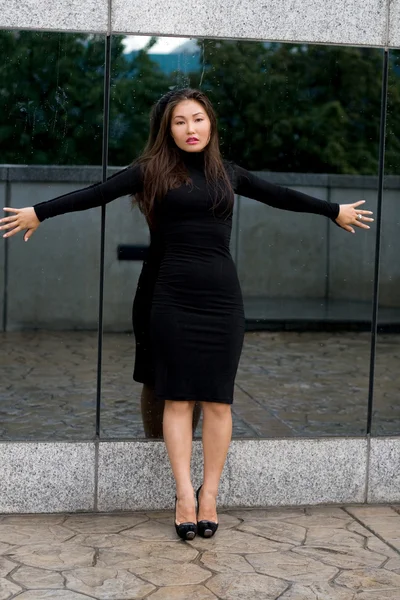 Сексуальная девушка в черном платье стоит перед зеркалом — стоковое фото