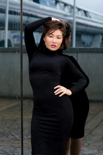 거울 앞에 서 있는 검은 드레스에 섹시 한 여자 — 스톡 사진